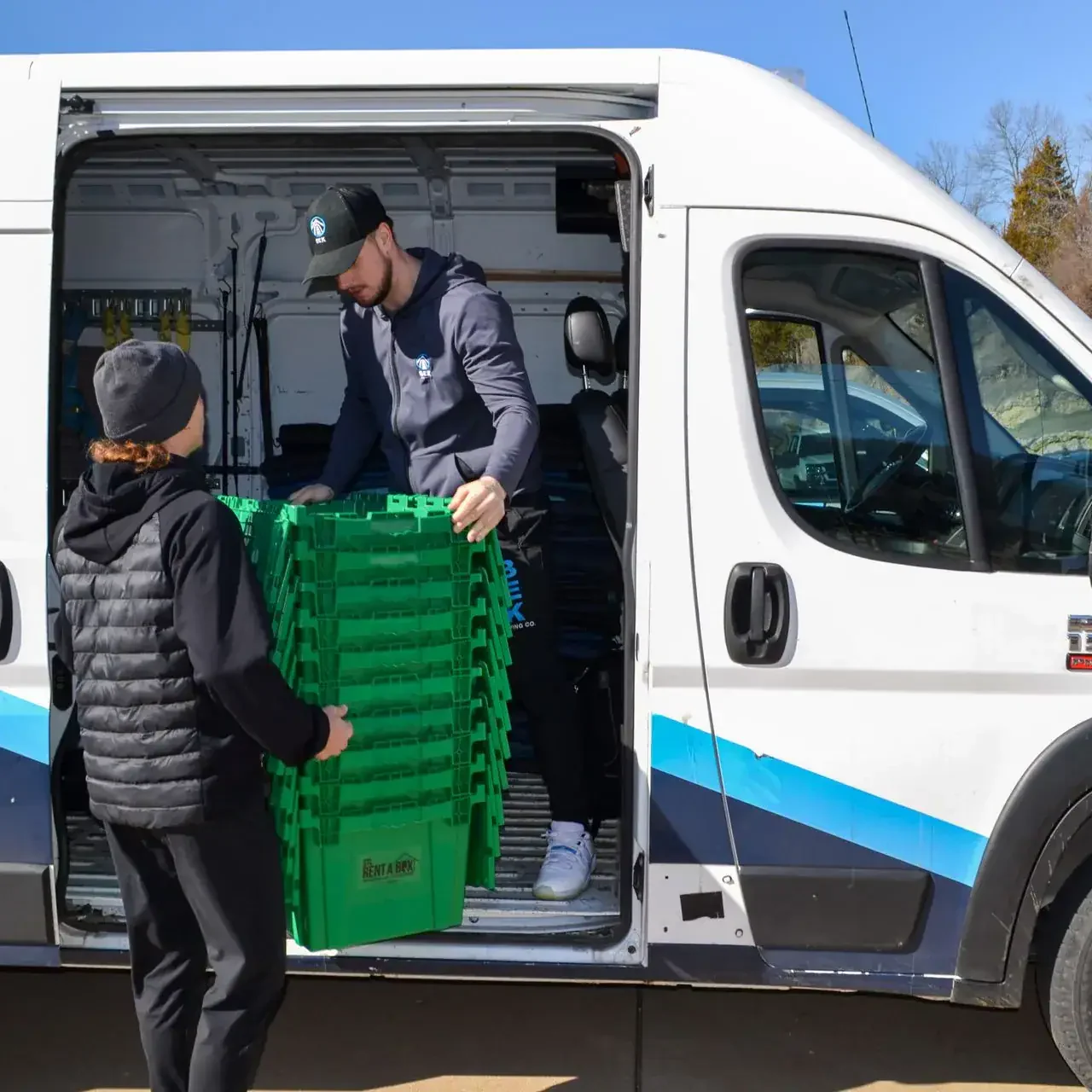 handing rentabox bins delivery van Workers loading green crates into delivery van