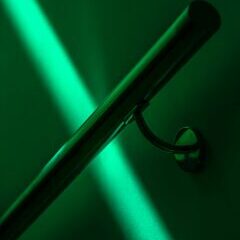 Green light illuminating metal rod on wall.