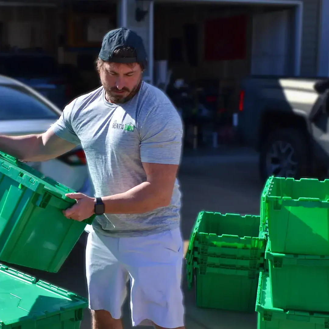 stacking rentabox green bins outdoor Man stacking green plastic storage bins outside.